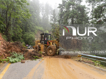 Workers are driving machinery to clear a collapsed road section at Bingmei Street in Congjiang county, Southwest China's Guizhou province, i...