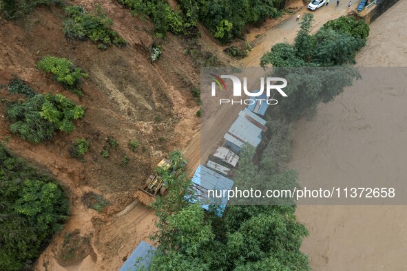 Workers are driving machinery to clear a collapsed road section at Bingmei Street in Congjiang county, Southwest China's Guizhou province, i...