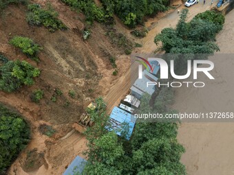 Workers are driving machinery to clear a collapsed road section at Bingmei Street in Congjiang county, Southwest China's Guizhou province, i...