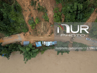 Workers are driving machinery to clear a collapsed road section at Bingmei Street in Congjiang county, Southwest China's Guizhou province, i...