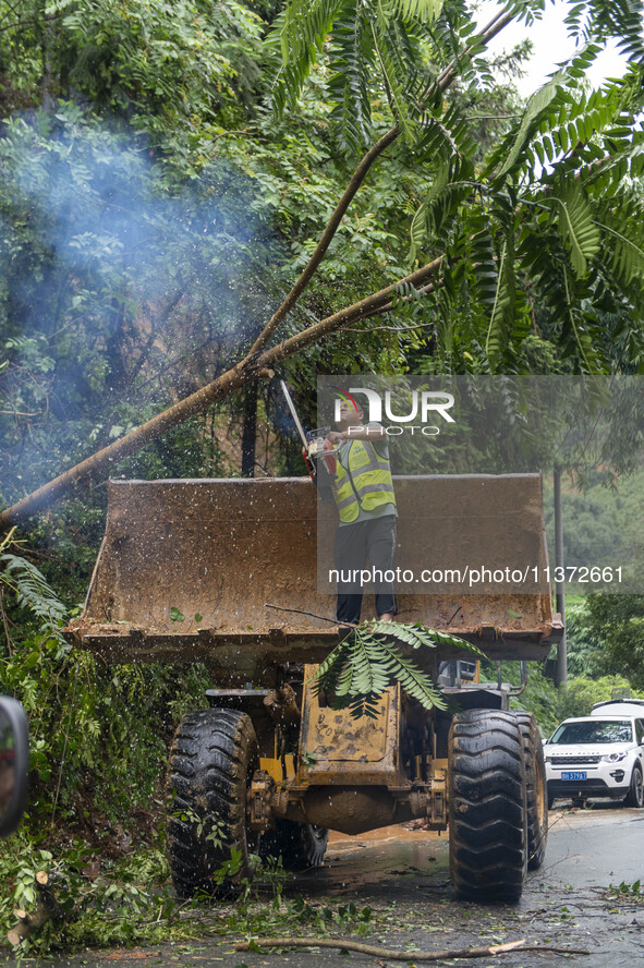 Workers are driving machinery to clear a collapsed road section at Bingmei Street in Congjiang county, Southwest China's Guizhou province, i...