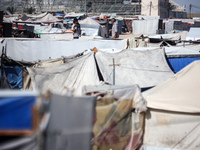 Palestinians are walking along an alley between tents sheltering displaced Palestinians in Rafah in the southern Gaza Strip on June 30, 2024...