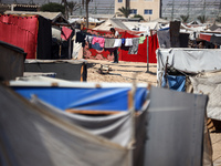 Palestinians are walking along an alley between tents sheltering displaced Palestinians in Rafah in the southern Gaza Strip on June 30, 2024...