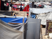 Palestinians are walking along an alley between tents sheltering displaced Palestinians in Rafah in the southern Gaza Strip on June 30, 2024...