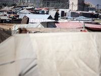 Palestinians are walking along an alley between tents sheltering displaced Palestinians in Rafah in the southern Gaza Strip on June 30, 2024...