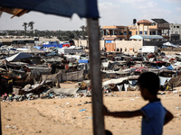 Palestinians are walking along an alley between tents sheltering displaced Palestinians in Rafah in the southern Gaza Strip on June 30, 2024...