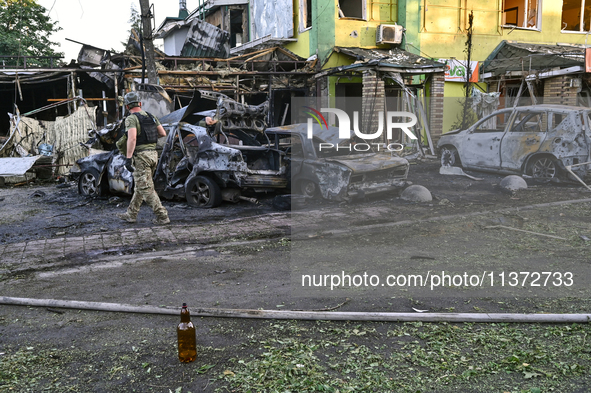 A man is walking past cars and a building destroyed by the Russian missile strike in central Vilniansk, Zaporizhzhia region, southern Ukrain...