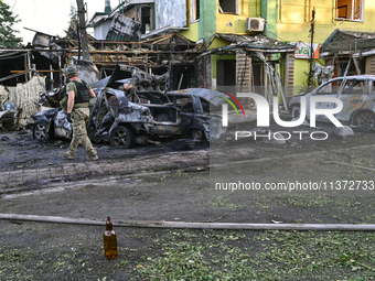 A man is walking past cars and a building destroyed by the Russian missile strike in central Vilniansk, Zaporizhzhia region, southern Ukrain...