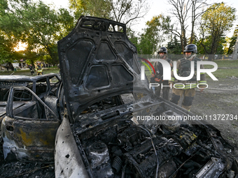 Rescuers are looking at a destroyed car during a response effort to the Russian missile attack in central Vilniansk, Zaporizhzhia region, so...