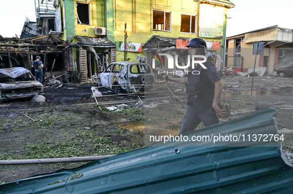 A man is walking past cars and a building destroyed by the Russian missile strike in central Vilniansk, Zaporizhzhia region, southern Ukrain...