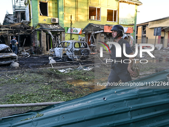 A man is walking past cars and a building destroyed by the Russian missile strike in central Vilniansk, Zaporizhzhia region, southern Ukrain...