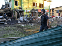 A man is walking past cars and a building destroyed by the Russian missile strike in central Vilniansk, Zaporizhzhia region, southern Ukrain...