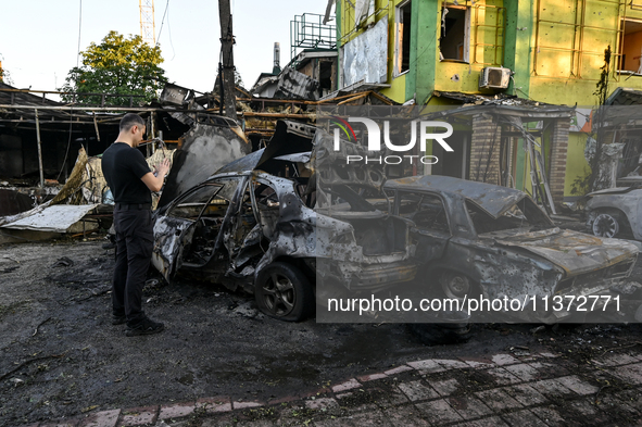 A man is standing by cars and a building wrecked by the Russian missile strike in central Vilniansk, Zaporizhzhia region, southern Ukraine,...