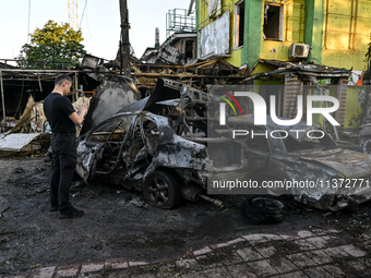 A man is standing by cars and a building wrecked by the Russian missile strike in central Vilniansk, Zaporizhzhia region, southern Ukraine,...