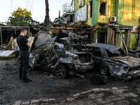 A man is standing by cars and a building wrecked by the Russian missile strike in central Vilniansk, Zaporizhzhia region, southern Ukraine,...