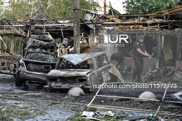 Burnt-out cars and a building are being pictured during a response effort to the Russian missile attack in central Vilniansk, Zaporizhzhia r...