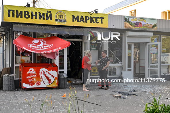 Two women are talking outside a shop damaged by the Russian missile attack in central Vilniansk, Zaporizhzhia region, southern Ukraine, on J...