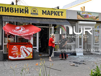 Two women are talking outside a shop damaged by the Russian missile attack in central Vilniansk, Zaporizhzhia region, southern Ukraine, on J...