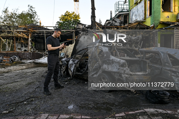 A man is standing by cars and a building wrecked by the Russian missile strike in central Vilniansk, Zaporizhzhia region, southern Ukraine,...