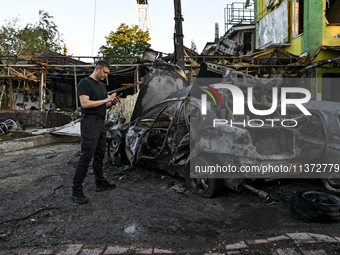 A man is standing by cars and a building wrecked by the Russian missile strike in central Vilniansk, Zaporizhzhia region, southern Ukraine,...