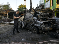 A man is standing by cars and a building wrecked by the Russian missile strike in central Vilniansk, Zaporizhzhia region, southern Ukraine,...