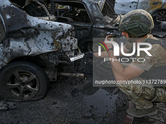 A criminal expert is examining a car destroyed by the Russian missile strike in central Vilniansk, Zaporizhzhia region, southern Ukraine, on...