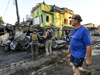 A man is walking past criminal experts who are examining cars destroyed by the Russian missile strike in central Vilniansk, Zaporizhzhia reg...