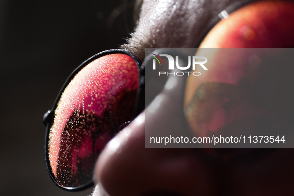 A woman poses as drops from water curtain are seen on her sunglasses during the heatwave in Krakow, Poland on June 30, 2024. 