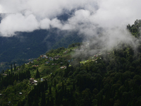 Small villages are being seen through clouds inside Singalila National Park in Darjeeling District, West Bengal, India, on June 29, 2024. (