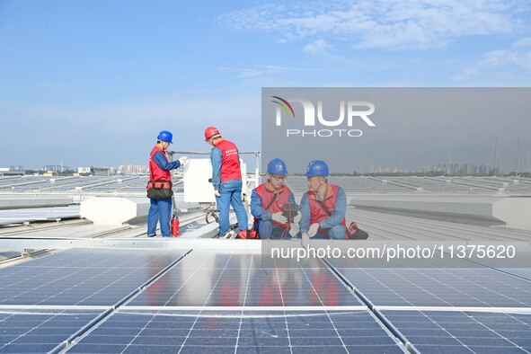 Power technicians are inspecting the operation of rooftop solar photovoltaic modules in Chuzhou, China, on June 30, 2024. 