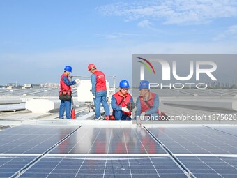 Power technicians are inspecting the operation of rooftop solar photovoltaic modules in Chuzhou, China, on June 30, 2024. (