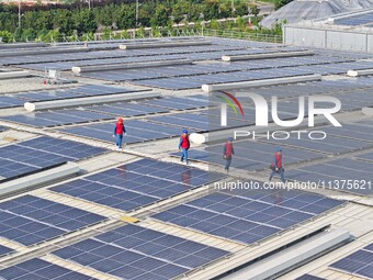 Power technicians are inspecting the operation of rooftop solar photovoltaic modules in Chuzhou, China, on June 30, 2024. (