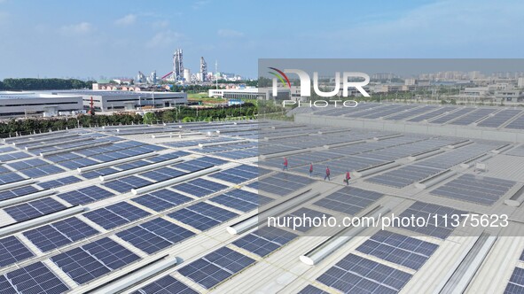 Power technicians are inspecting the operation of rooftop solar photovoltaic modules in Chuzhou, China, on June 30, 2024. 