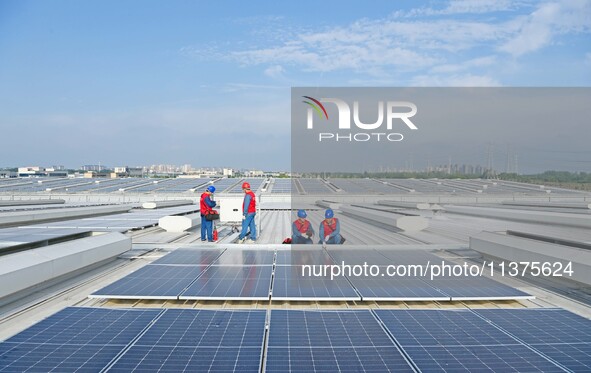 Power technicians are inspecting the operation of rooftop solar photovoltaic modules in Chuzhou, China, on June 30, 2024. 