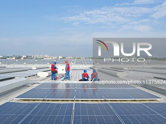 Power technicians are inspecting the operation of rooftop solar photovoltaic modules in Chuzhou, China, on June 30, 2024. (