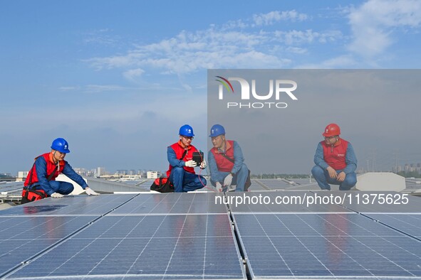 Power technicians are inspecting the operation of rooftop solar photovoltaic modules in Chuzhou, China, on June 30, 2024. 