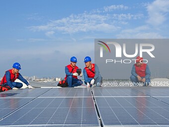 Power technicians are inspecting the operation of rooftop solar photovoltaic modules in Chuzhou, China, on June 30, 2024. (