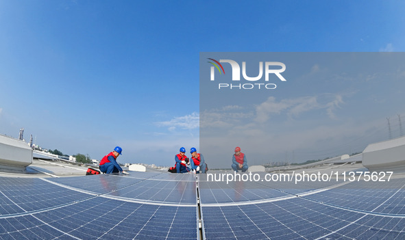 Power technicians are inspecting the operation of rooftop solar photovoltaic modules in Chuzhou, China, on June 30, 2024. 