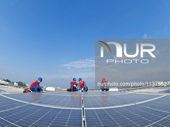 Power technicians are inspecting the operation of rooftop solar photovoltaic modules in Chuzhou, China, on June 30, 2024. (