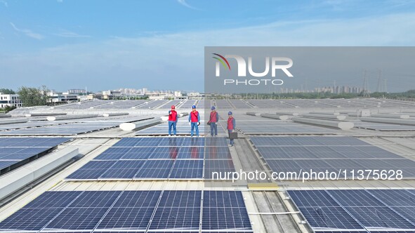 Power technicians are inspecting the operation of rooftop solar photovoltaic modules in Chuzhou, China, on June 30, 2024. 