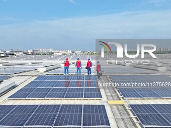 Power technicians are inspecting the operation of rooftop solar photovoltaic modules in Chuzhou, China, on June 30, 2024. (