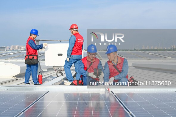 Power technicians are inspecting the operation of rooftop solar photovoltaic modules in Chuzhou, China, on June 30, 2024. 