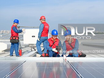 Power technicians are inspecting the operation of rooftop solar photovoltaic modules in Chuzhou, China, on June 30, 2024. (