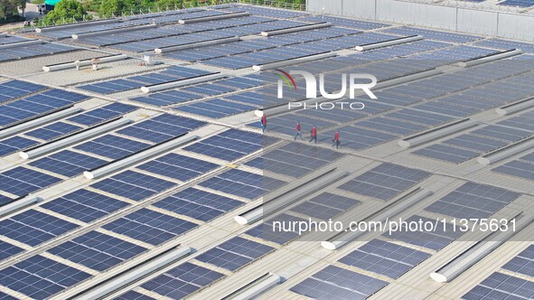 Power technicians are inspecting the operation of rooftop solar photovoltaic modules in Chuzhou, China, on June 30, 2024. 