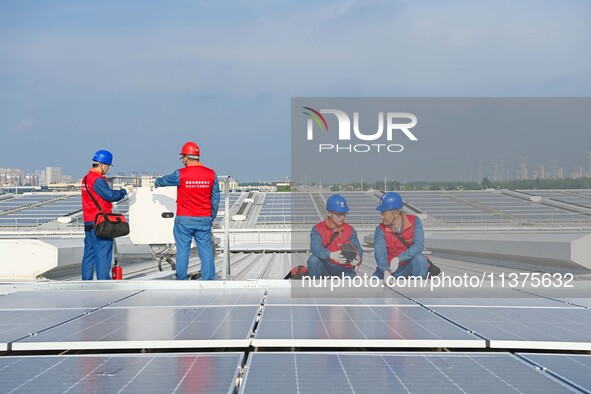 Power technicians are inspecting the operation of rooftop solar photovoltaic modules in Chuzhou, China, on June 30, 2024. 