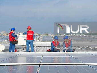 Power technicians are inspecting the operation of rooftop solar photovoltaic modules in Chuzhou, China, on June 30, 2024. (