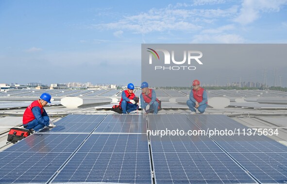 Power technicians are inspecting the operation of rooftop solar photovoltaic modules in Chuzhou, China, on June 30, 2024. 