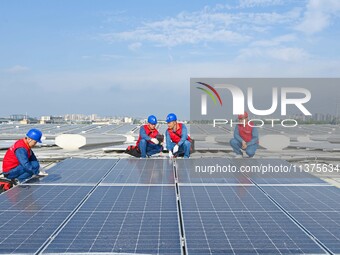 Power technicians are inspecting the operation of rooftop solar photovoltaic modules in Chuzhou, China, on June 30, 2024. (