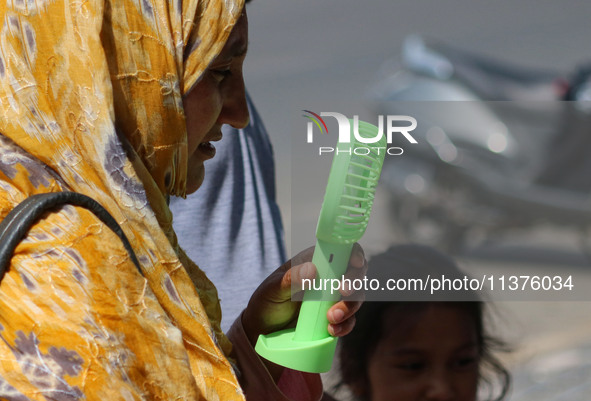 A woman is cooling off herself with a battery fan on a hot summer day in Srinagar, Jammu And Kashmir, on July 01, 2024. 