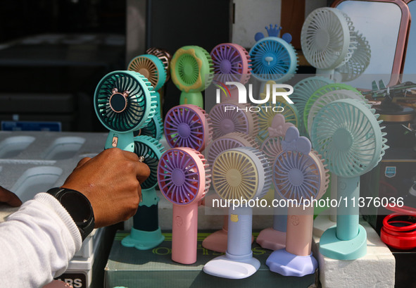 A man is arranging battery fans on a hot summer day in Srinagar, Jammu And Kashmir, on July 01, 2024. 